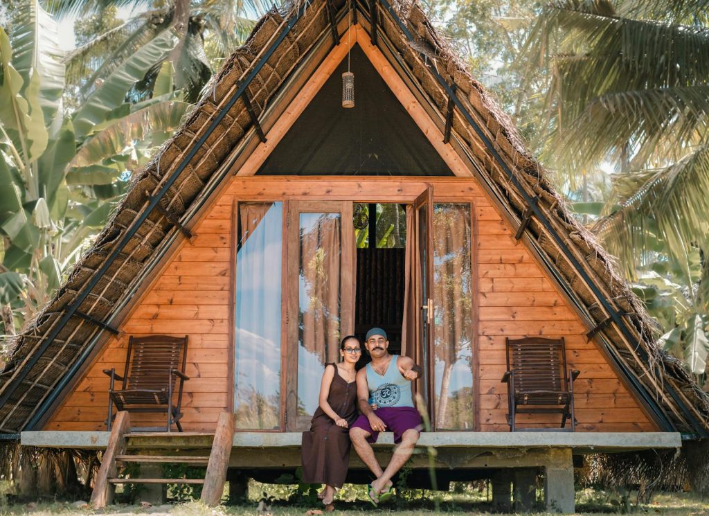 A couple enjoying the tropical view from their rustic wooden bungalow in Sri Lanka.